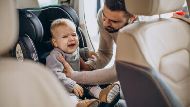 father putting daughter in a car seat