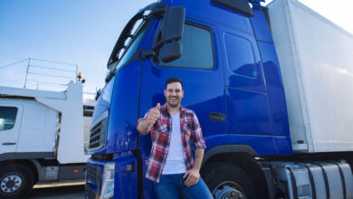 professional truck driver in front of long transportation vehicle holding thumbs up ready for a new ride