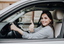 beautiful young latin woman driving her brand new car and showing her thumb up