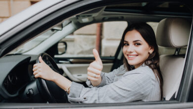 beautiful young latin woman driving her brand new car and showing her thumb up