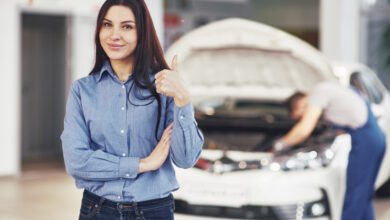 the woman approves the work done by the client the mechanic works under the hood of the car