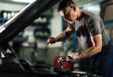 mecanico adulto medio examinando o oleo do carro na oficina de reparacao automovel