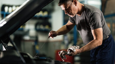 mecanico adulto medio examinando o oleo do carro na oficina de reparacao automovel